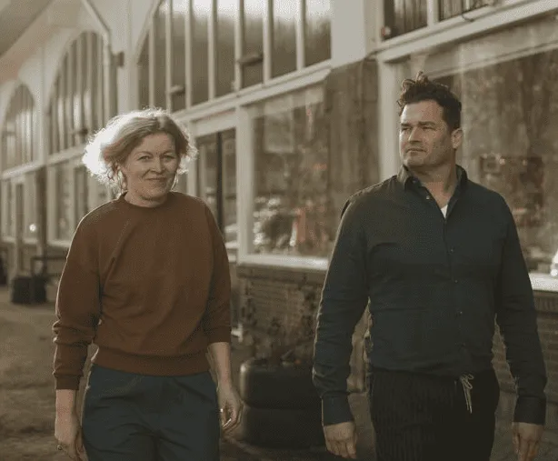 Moderne receptiebalie met terrazzo-look en een golvende lichtinstallatie aan het plafond, onderdeel van een strak en toekomstbestendig kantoorontwerp.