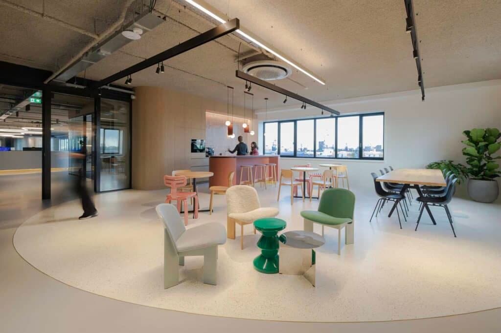 Sfeervolle kantoorinrichting in Tilburg met organische vormen, diverse design stoelen en een duurzame, biobased pantry op de achtergrond.
